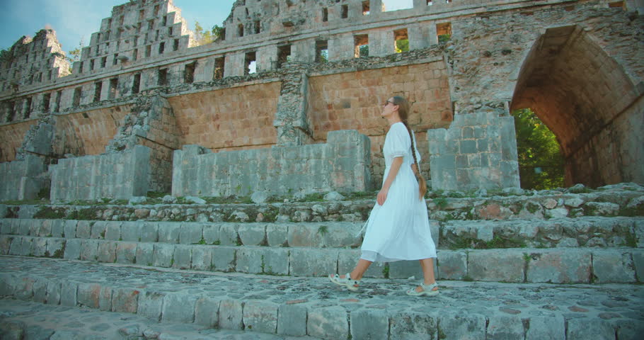 Woman in white exploring stone Mayan ruins and arched structure in Mexico