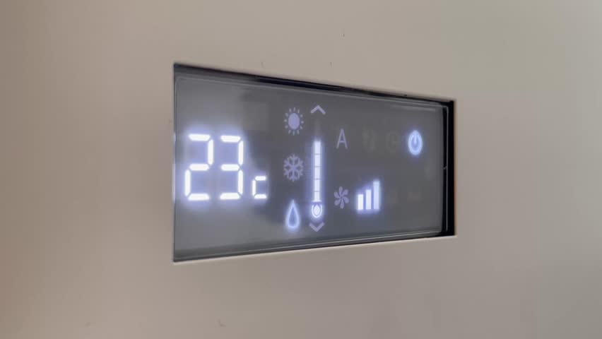 Digital air conditioner screen turning on and cooling set to 23 degrees Celsius. Concept of summer heat relief and indoor comfort.