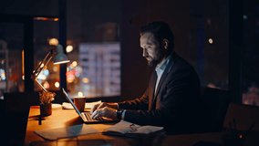 Overworked man typing laptop checking papers at evening workspace closeup. Serious businessman working late looking computer in office. Smart lawyer thinking decision analyzing reports alone at night  - Powered by Shutterstock - Get 15% off with code: PIKWIZARD15