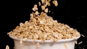 Oat grains cascade into a white bowl against a black background, highlighting texture and motion in a 13-second video - Powered by Shutterstock - Get 15% off with code: PIKWIZARD15