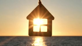 Silhouette of wooden house keychain on background of sea sunset. Mortgage, home loan, real estate purchase, sale and rent. Sweet home for family. Solar energy concept - Powered by Shutterstock - Get 15% off with code: PIKWIZARD15