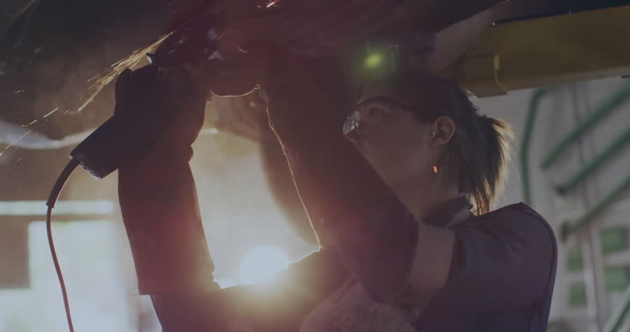 Metal fabricator operating angle grinder sparking, activating digital icons emerging around grinder. Industrial, engineering, technology, innovation, manufacturing, futuristic, workshop