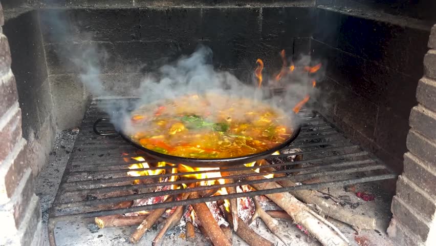 Traditional paella slowly simmering on crackling wood fire, radiating smoky aroma and authentic Flavors of Spanish culinary heritage, creating mouthwatering mediterranean meal