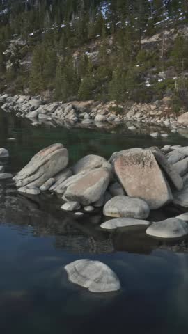 Lake Tahoe, USA: Smooth boulders sit in the clear water of Lake Tahoe. People gather on the rocky shoreline to enjoy the view and the natural beauty of the lake.