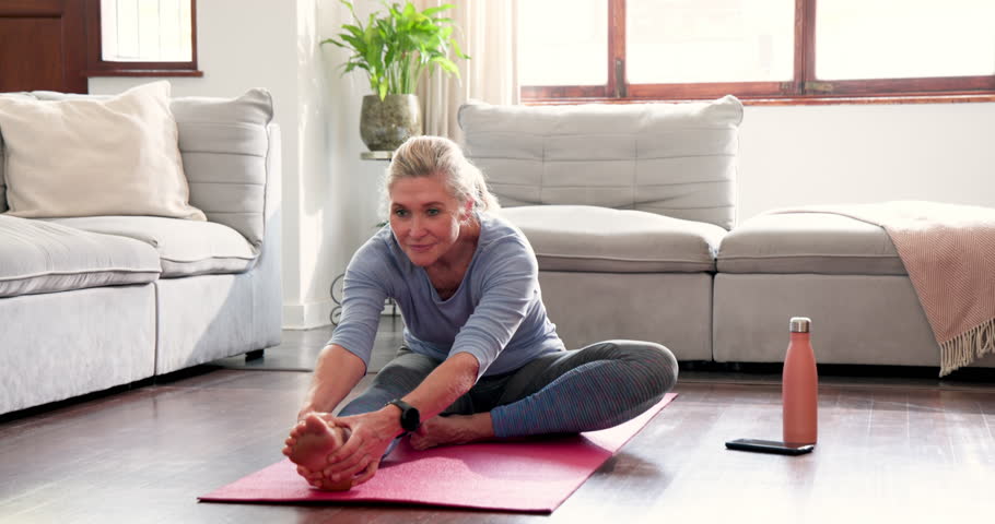 Senior woman stretching on yoga mat at home, enjoying peaceful exercise routine. Wellness, fitness, elderly, relaxation, home workout, meditation