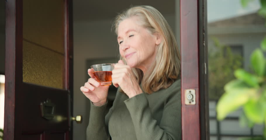 Smiling senior woman enjoying tea by window, embracing peaceful moment at home. Relaxation, tranquility, elderly, lifestyle, beverage, indoors