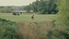 A male golfer hits a fairway shot out of the rough with a divot flying. His female partner stands beside a golf cart in the background, watching. A dynamic two-player golf moment in real time. - Powered by Shutterstock - Get 15% off with code: PIKWIZARD15