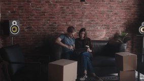 Couple using tablet and drinking coffee on couch in new apartment with boxes. - Powered by Shutterstock - Get 15% off with code: PIKWIZARD15