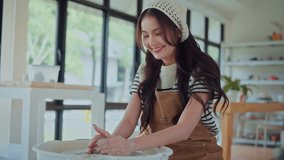 Young asian woman sculpting clay on spinning pottery wheel in ceramic workshop – relaxing creative hobby, art class activity, and handmade design practice in craft studio environment - Powered by Shutterstock - Get 15% off with code: PIKWIZARD15