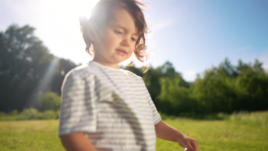 Young girl field holding pair of sunglasses. Girl holding sunglasses in the grass. A tree in the summer with sunlight and nature in the outdoors. A girl in a meadow is holding a pair of lifestyle.