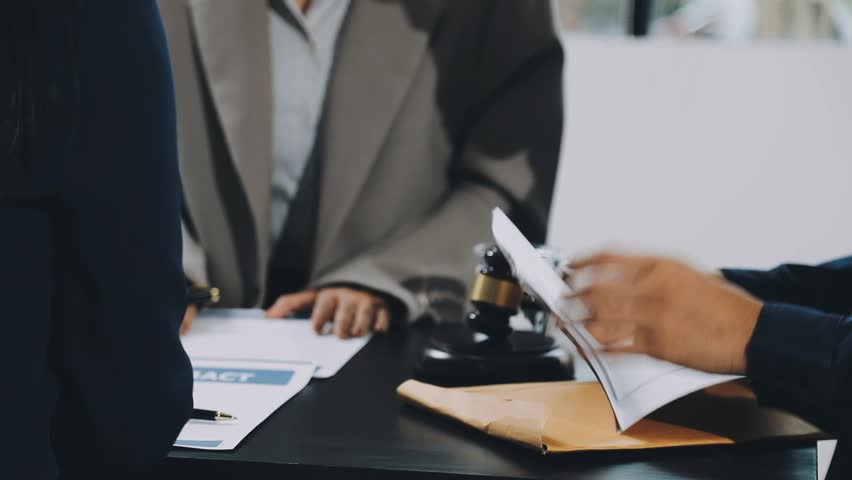 Business and lawyers discussing contract papers with brass scale on desk in office. Law, legal services, advice, justice and law concept picture with film grain effect