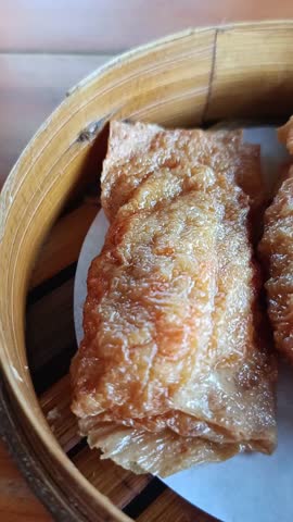 Fried beancurd skin rolls, a popular dim sum dish, served in a bamboo steamer.
