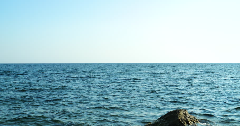 Wide cinematic establishing shot captures the tranquil Mediterranean Sea horizon with rocky shoreline in crisp 4K DCI, ideal for film and background intro ad