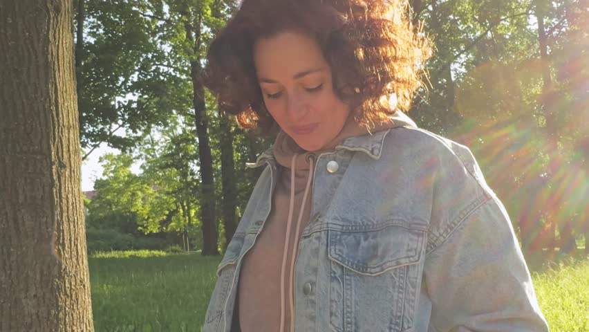 Beautiful young woman smiling laughing on sunset in city park. Outdoor portrait of young happy smiling girl. Woman enjoying summer sunny day relaxing outdoor. Freedom happiness carefree happy people