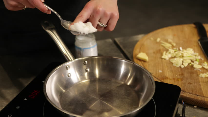 Coconut oil, spoonful adding, stainless pan. Close-up adding spoonful coconut oil to stainless steel pan. Process melting coconut oil is common step in preparing variety dishes, highlighting healthy
