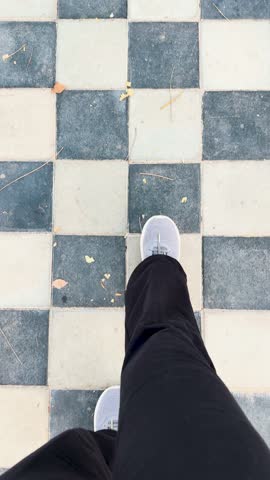 4K Vertical POV shot of Women's legs in trek pant and shoes on street tiles at walking trek. Copy space, top view, personal point of view. Morning walk and heathy lifestyle concept.

