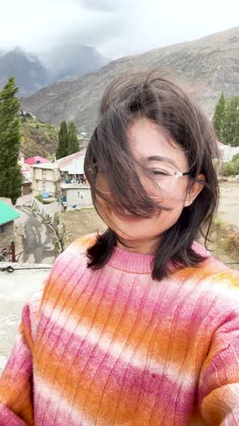 4K Vertical selfie video of Indian female tourist enjoying fresh air in mountains during summer holidays at Keylong, Himachal Pradesh, India. Happy Indian travel blogger smiling at camera. 