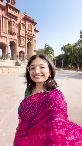 4K vertical selfie video of Indian woman wearing saree and vlogging while standing at Patrika Gate in Jaipur, Rajasthan, India. Travel blogger making content on location. Old Indian architecture.