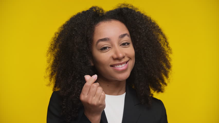 Smirking woman making money gesture on yellow