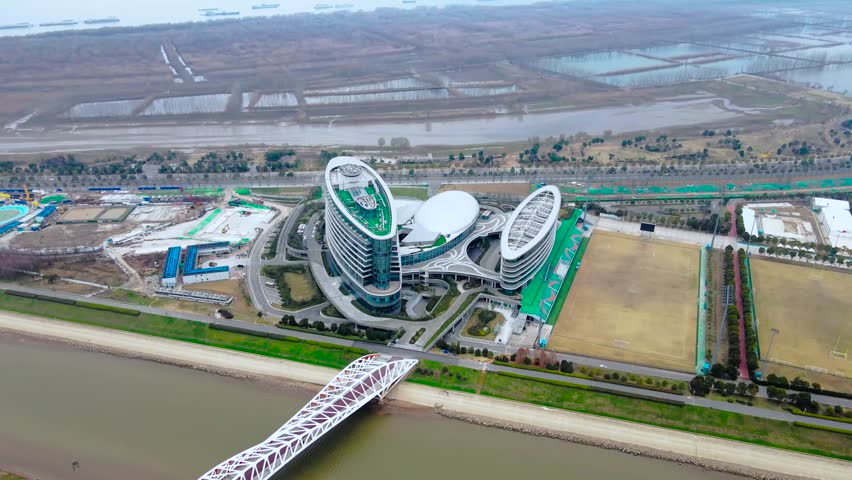 Explore the breathtaking aerial view of the Yangtze River featuring a contemporary structure in Nanjing Jiangbei New Area. Witness the stunning landscape and river meandering.