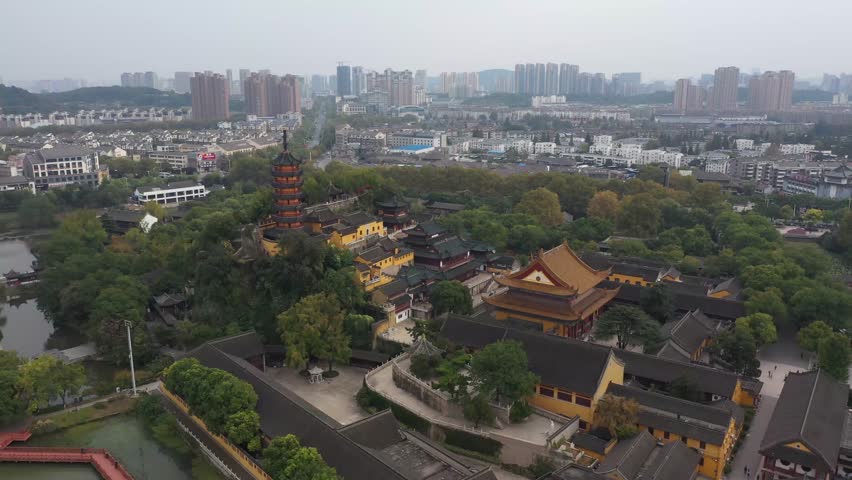 This aerial perspective showcases Jinshan Temple, a national scenic spot in Zhenjiang, Jiangsu Province. The vibrant temple integrates harmoniously with the surrounding greenery and urban landscape.