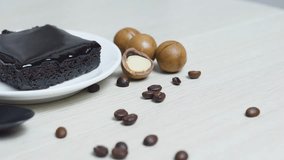 Rich chocolate brownie drizzled with dark ganache, resting on white plate, surrounded by roasted coffee beans and macadamia nuts on rustic wooden surface - Powered by Shutterstock - Get 15% off with code: PIKWIZARD15