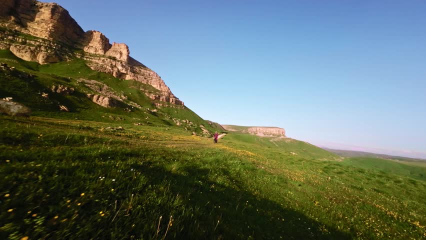 Young male rider doing wheelie on his bicycle in mountains. Aerial view from fpv drone with epic rocky mountains
