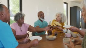 Adult group passing plates and sipping coffee as user-triggered social media emojis rising on table. Social gathering, family reunion, communal dining, casual celebration, candid interaction, modern - Powered by Shutterstock - Get 15% off with code: PIKWIZARD15