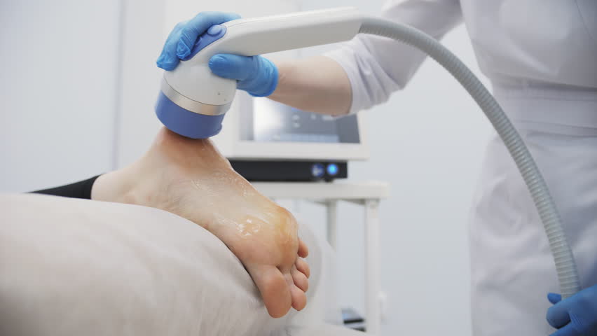 Shockwave therapy applied to foot with gel in clinic