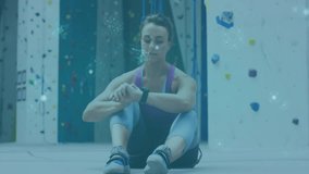 Climber sitting in gym raising arm using smartwatch and swirling blue metrics monitoring fitness. Athlete, wearable technology, digital interface, fitness tracker, health monitoring, activewear, - Powered by Shutterstock - Get 15% off with code: PIKWIZARD15