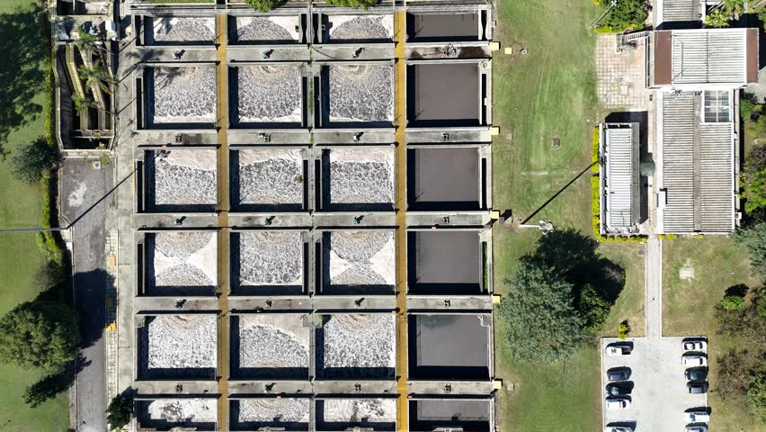 Aerial drone video of activated sludge tanks at an industrial sanitation facility. Wastewater treatment captured from above with visible circular infrastructure