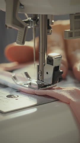 A talented craftswoman carefully operates a sewing machine to stitch together fabric pieces in a textile factory. The detail showcases her expertise in clothing production
