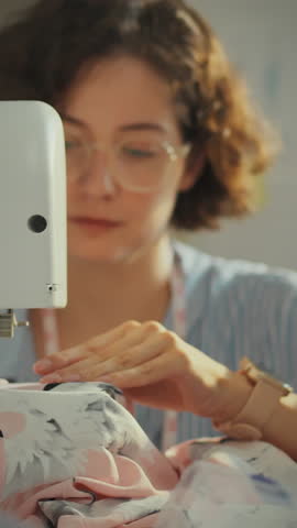 A creative individual concentrates on sewing clothing patterns using a sewing machine in a stylish design studio. The atmosphere is vibrant and inspiring, reflecting artistic dedication