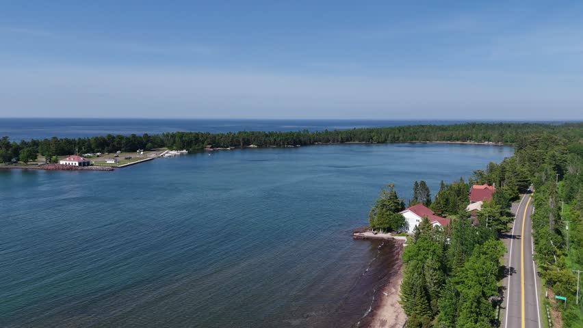 Upper Peninsula aerial beach scene with mist coming off the water and a boat driving through the bay.