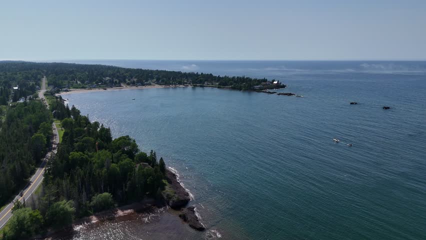 Upper Peninsula aerial beach scene with mist coming off the water and a boat driving through the bay.