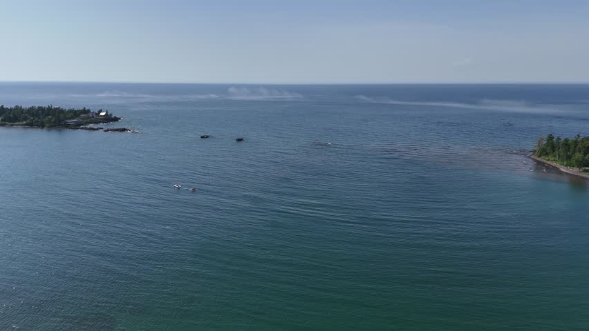 Upper Peninsula aerial beach scene with mist coming off the water and a boat driving through the bay.