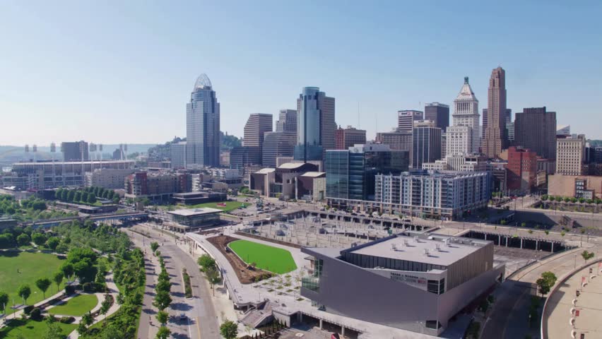 Aerial views of Cincinnati Ohio showcasing downtown skyline Mount Adams and the Ohio River during sunny weather capturing bridges city buildings urban landscape and scenic riverfront environment.