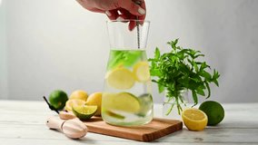 Lemonade with lemons, limes and fresh mint. Female hand mixing summer refreshing, homemade lemonade.  - Powered by Shutterstock - Get 15% off with code: PIKWIZARD15