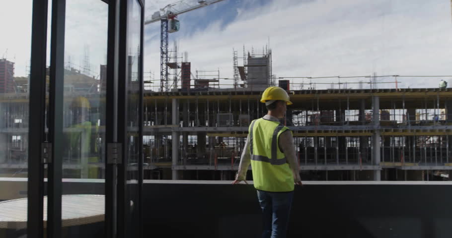 Site engineer stepping onto glass panel and scanning building for safety with AR overlays updating. Construction, technology, innovation, safety, industry, architecture, infrastructure