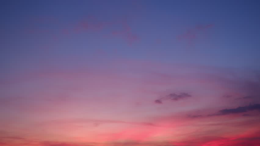 A captivating sunrise sky timelapse with soft pink and purple clouds glowing gently against a fading dark blue sky, evoking a peaceful and hopeful start to the day as light slowly spreads. Time-lapse.