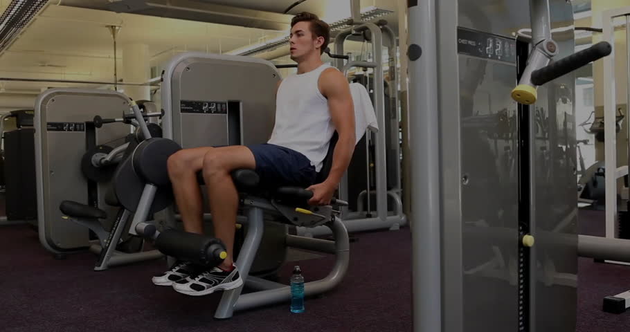 Man adjusting leg extension handles and initiating quadriceps exercise for muscle growth in fitness. Strength, stamina, endurance, training, gym, fitness, wellness