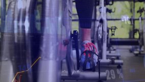 Stepping onto bike, woman biking in gym with animated line graphs, bar charts reflecting intensity. Fitness, performance, digital, vitality, motivation, wellness, activity - Powered by Shutterstock - Get 15% off with code: PIKWIZARD15