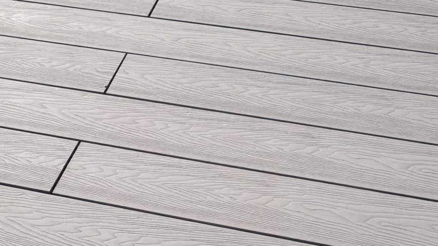 Close-up of light gray composite decking with pronounced wood texture. The surface appears modern and neat, perfect for outdoor relaxation areas and stylish architectural solutions
