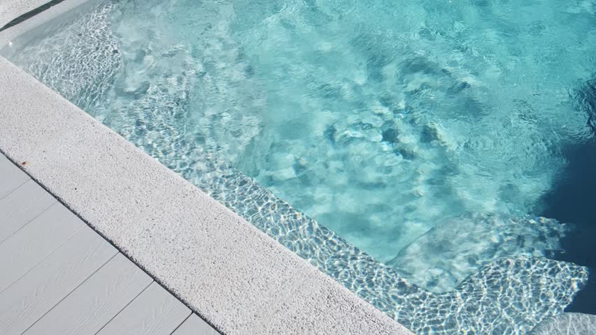 Clear blue water in a private tiled pool with underwater steps and bright sunlight reflections creates an atmosphere of cleanliness, comfort, and summer outdoor relaxation
