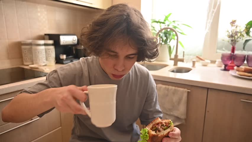Two teenage brothers eat burgers at home with their mother. 