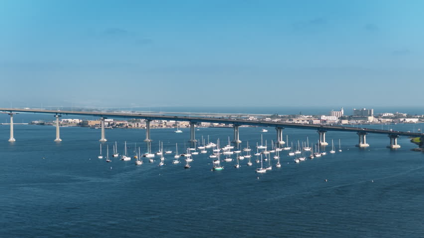 Experience the stunning aerial footage of Downtown San Diego, perfectly showcasing the beautiful bay, the majestic bridge, and the numerous sailboats gliding across the water. A true visual delight