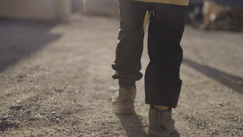 Slow motion close-up of a child’s hiking boots walking on dusty ground during a trekking adventure in the High Atlas mountains of Morocco, capturing each step with precision and highlighting the spiri