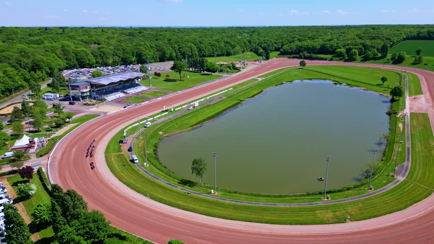 Aerial view of a harness horse race in progress at the Hippodrome de Laval Bellevue-La Forêt, with horses pulling sulkies around the track, France