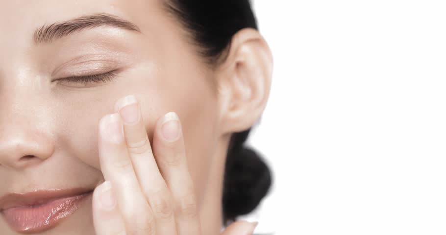 A close-up of a young woman smiling brightly and gently touching her face, showing radiant, healthy skin. Perfect for promoting skincare, wellness, and beauty products focused on natural glow and self