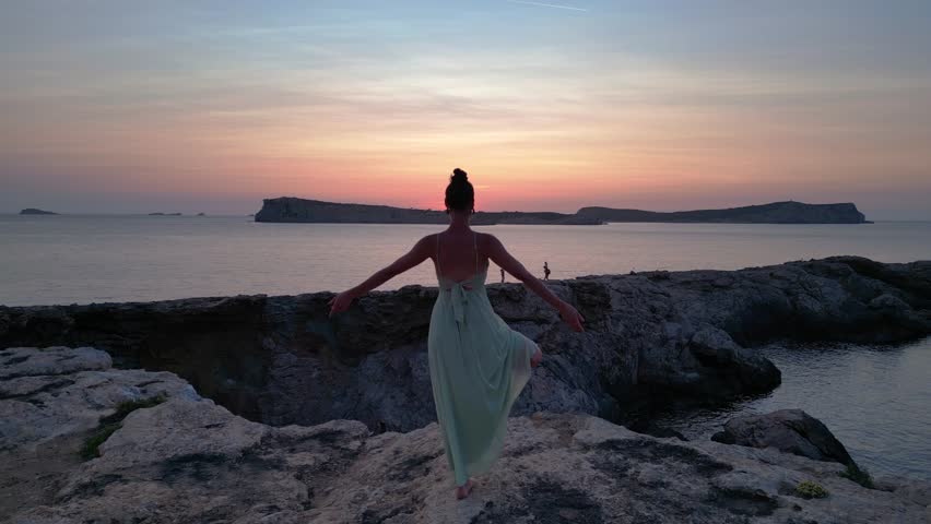Yoga Hippie Girl at sunset with island in the background, Ibiza, Spain. Majestic aerial view flight ascending drone